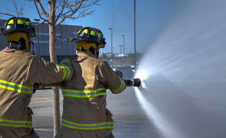 Firefighters spraying hose on scene 