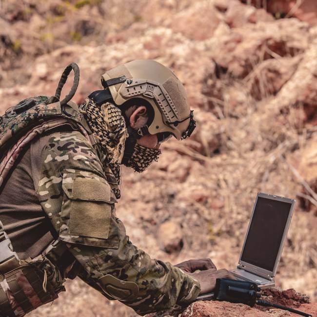 Soldier working on computer in desert