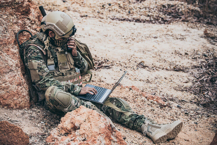 Soldier working on computer in desert